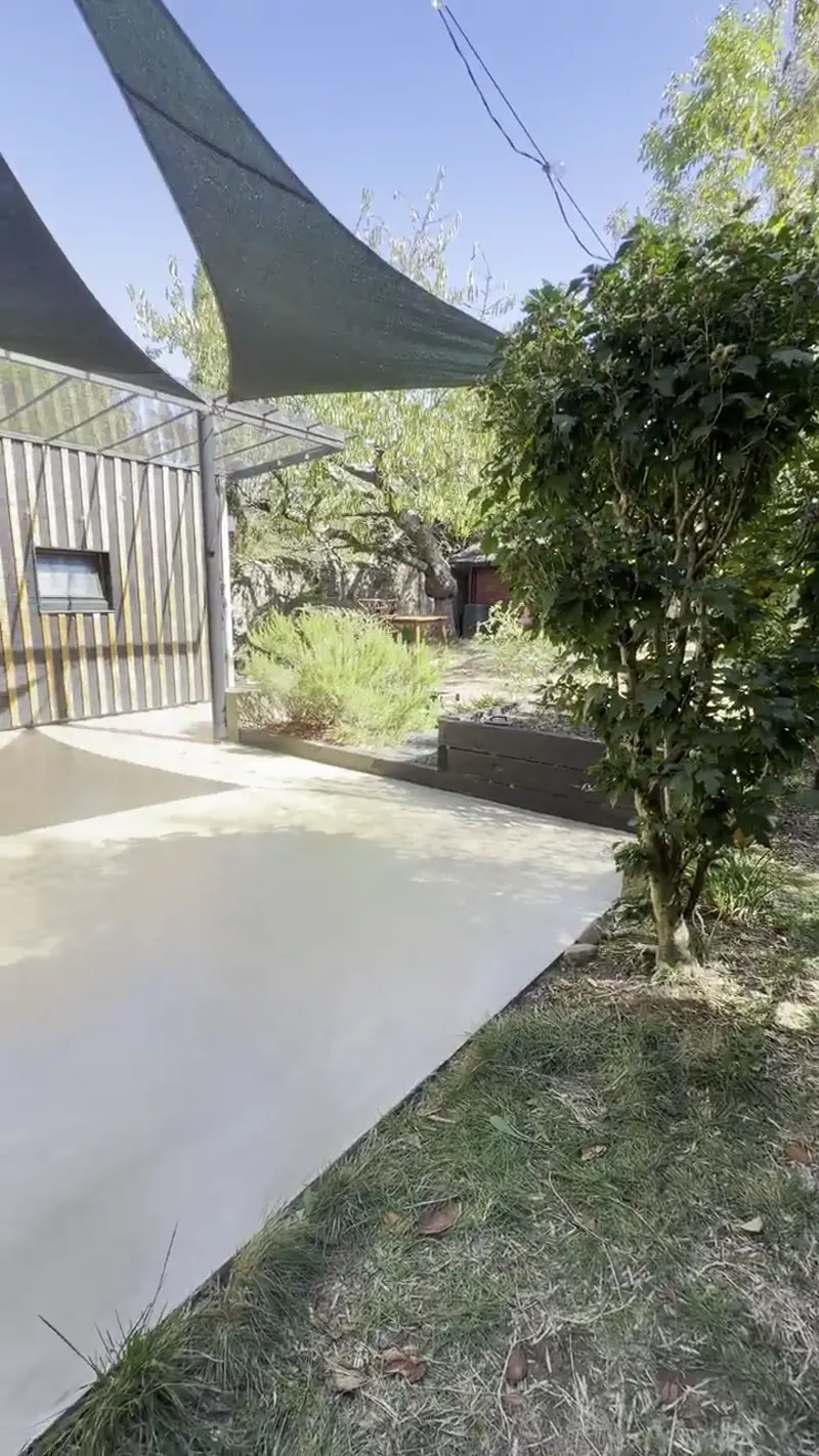 Terrasse en béton ciré sous pergola et voile d'ombrage