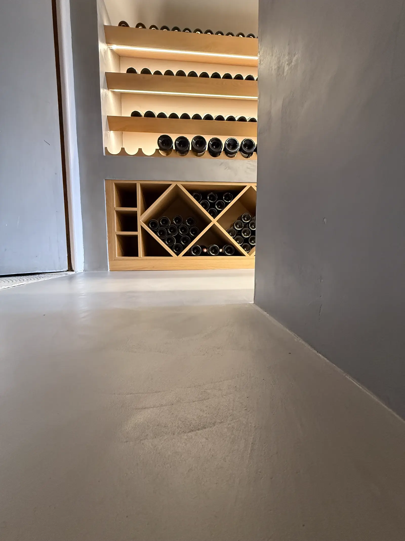 Cave à vin en béton ciré avec casiers à bouteilles en bois en forme de losange