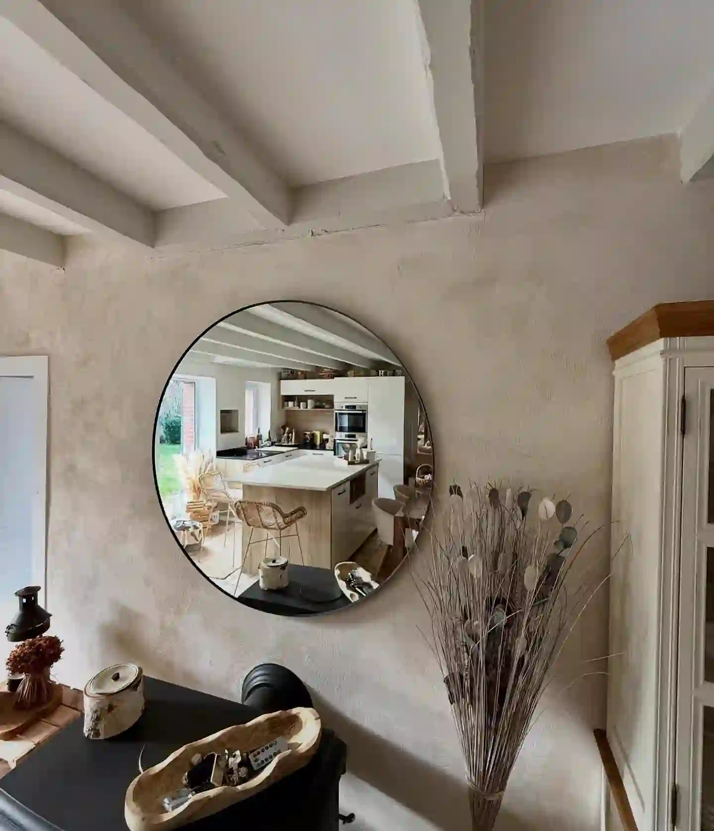Mur en enduit à la chaux avec miroir rond, reflet d'une cuisine
