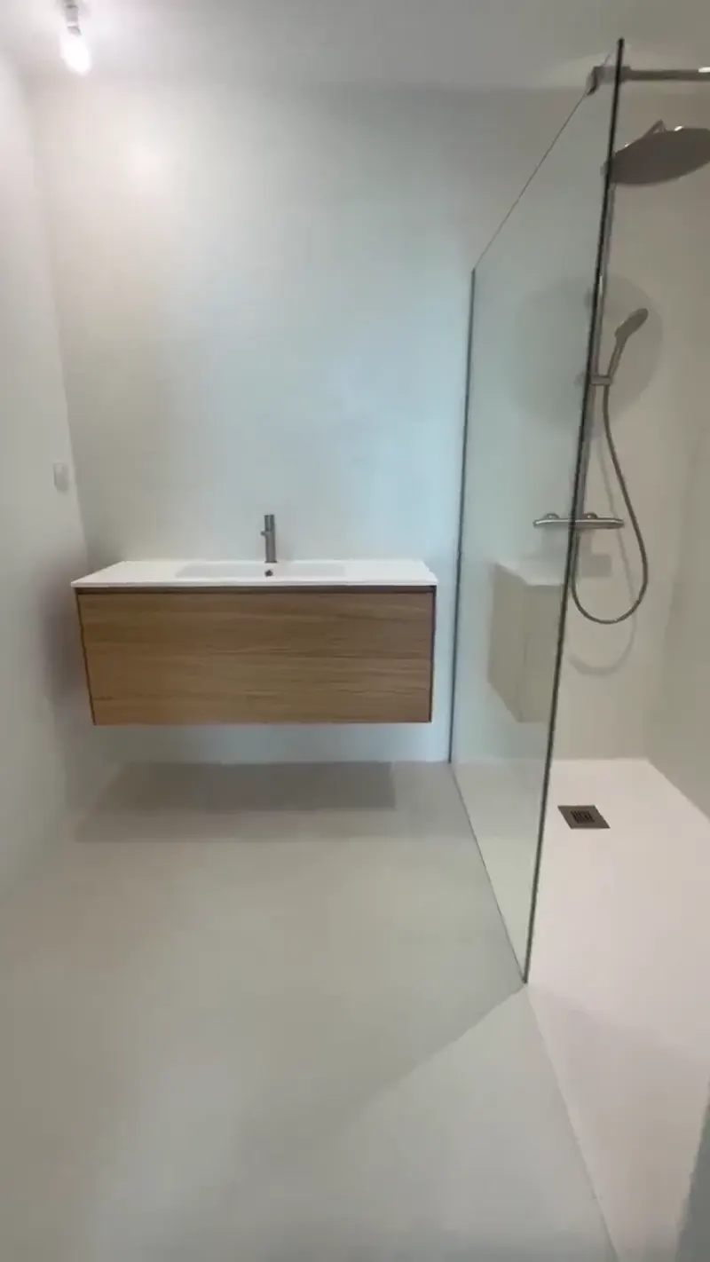Douche à l'italienne minimaliste en béton ciré avec meuble vasque en bois