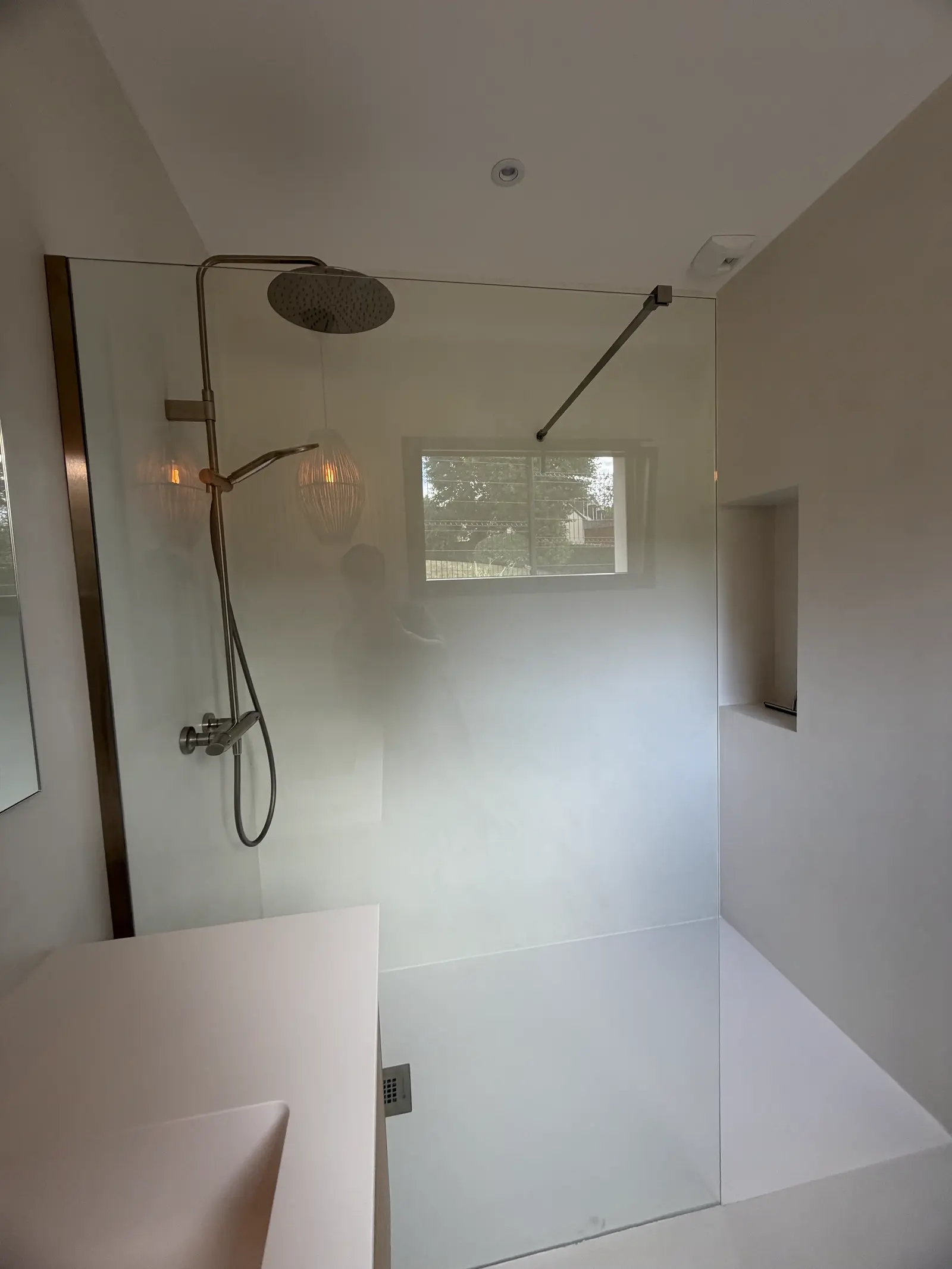 Douche à l'italienne en béton ciré avec niche intégrée et vue sur jardin