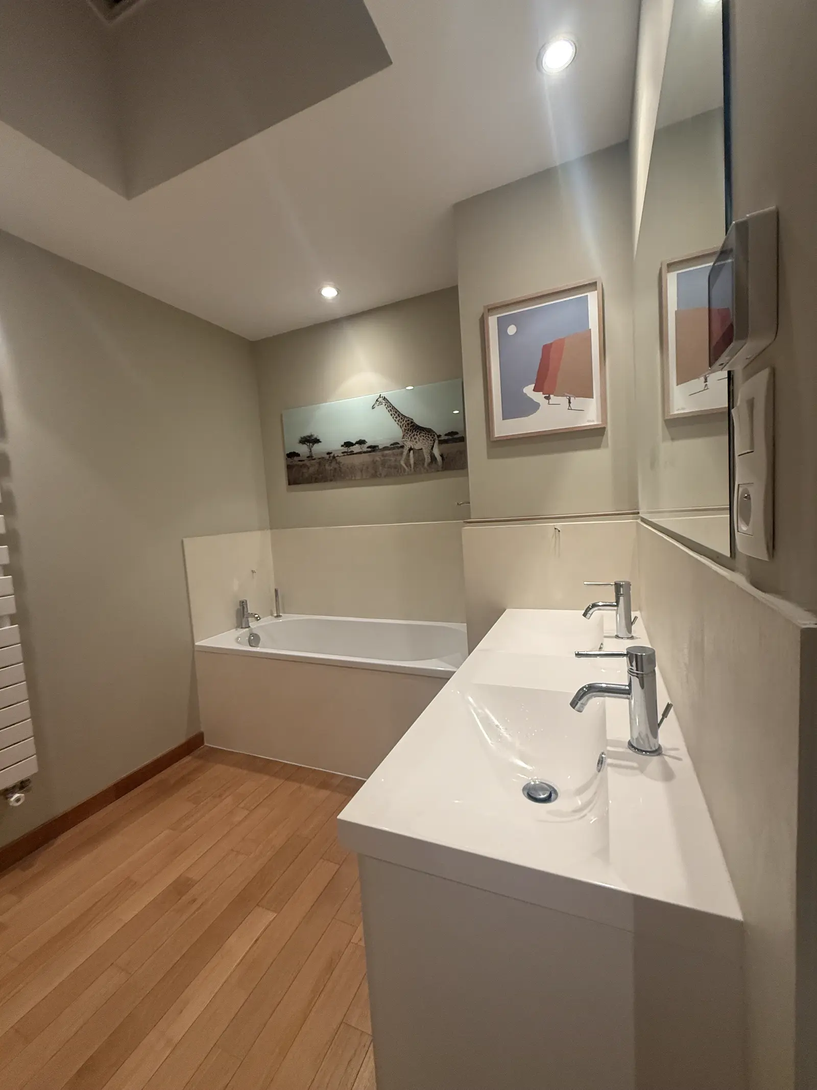 Salle de bain avec baignoire, double vasque et sol parquet