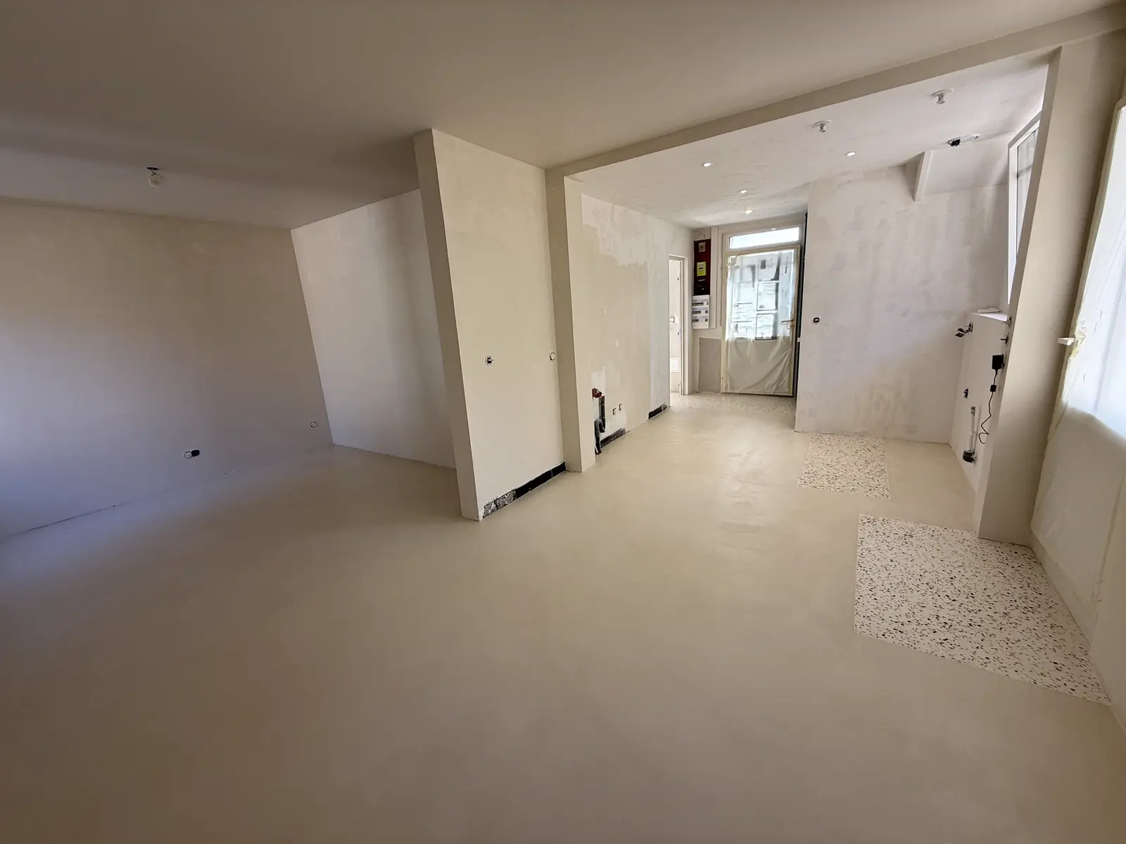 Couloir avec sol en béton ciré beige, murs bruts en cours de finition