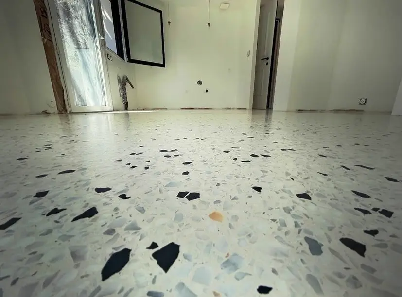 Sol en terrazzo clair dans une pièce vide avec porte-fenêtre
